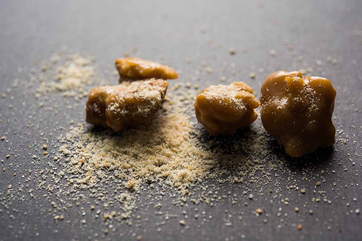 A close up horizontal image of asafetida cake and powder on a dark gray surface.