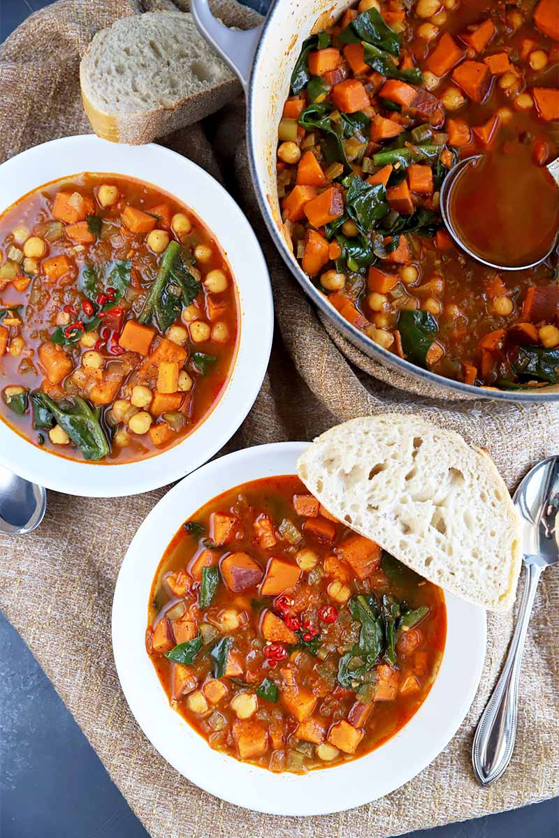 A vertical image of three bowls of sweet potato and tatsoi soup ready to eat.