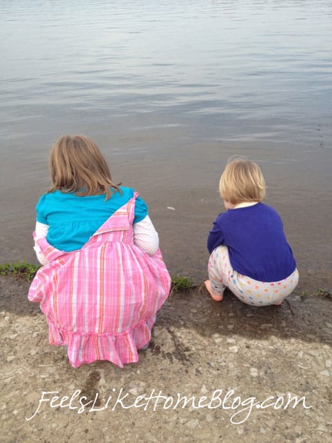 A little girl standing next to a body of water