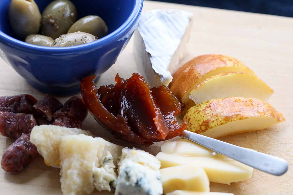 A close up horizontal image of a charcuterie board with fruit and cheese.